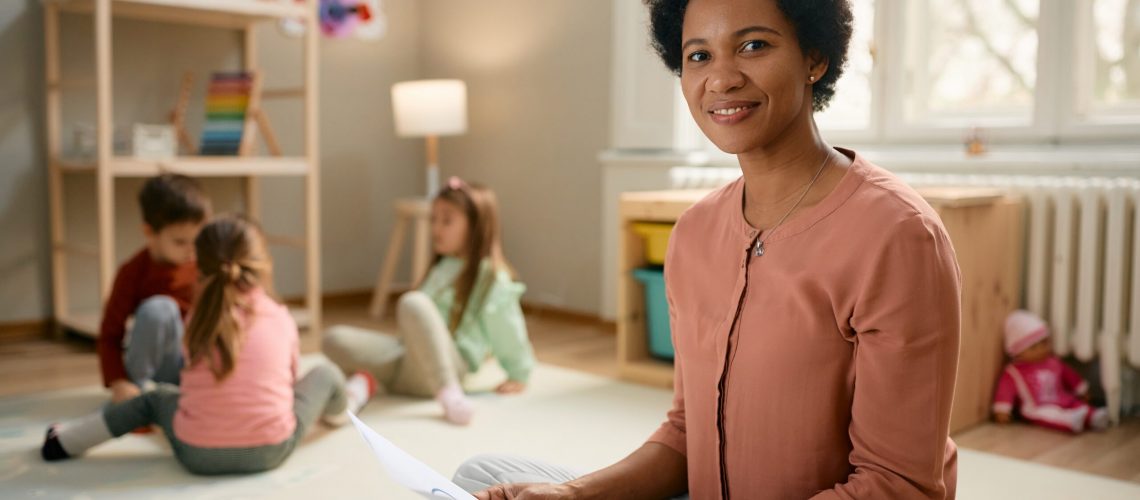 Smiling,African,American,Preschool,Teacher,Sitting,On,The,Floor,And